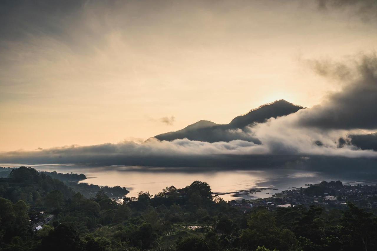 Scenic view of a lake with misty mountains in the background at sunrise.